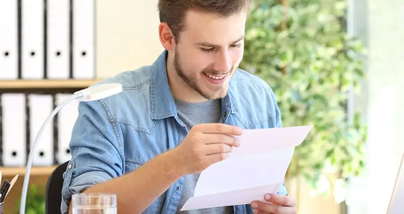 Man with big smile reading mail