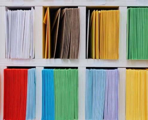 Envelopes stacks sorted on a shelf by color_