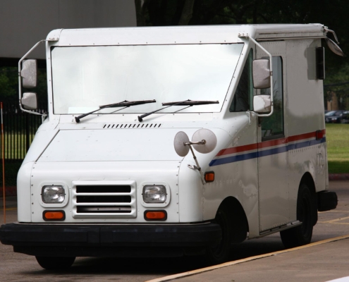 Side view of a mail truck driving down the road