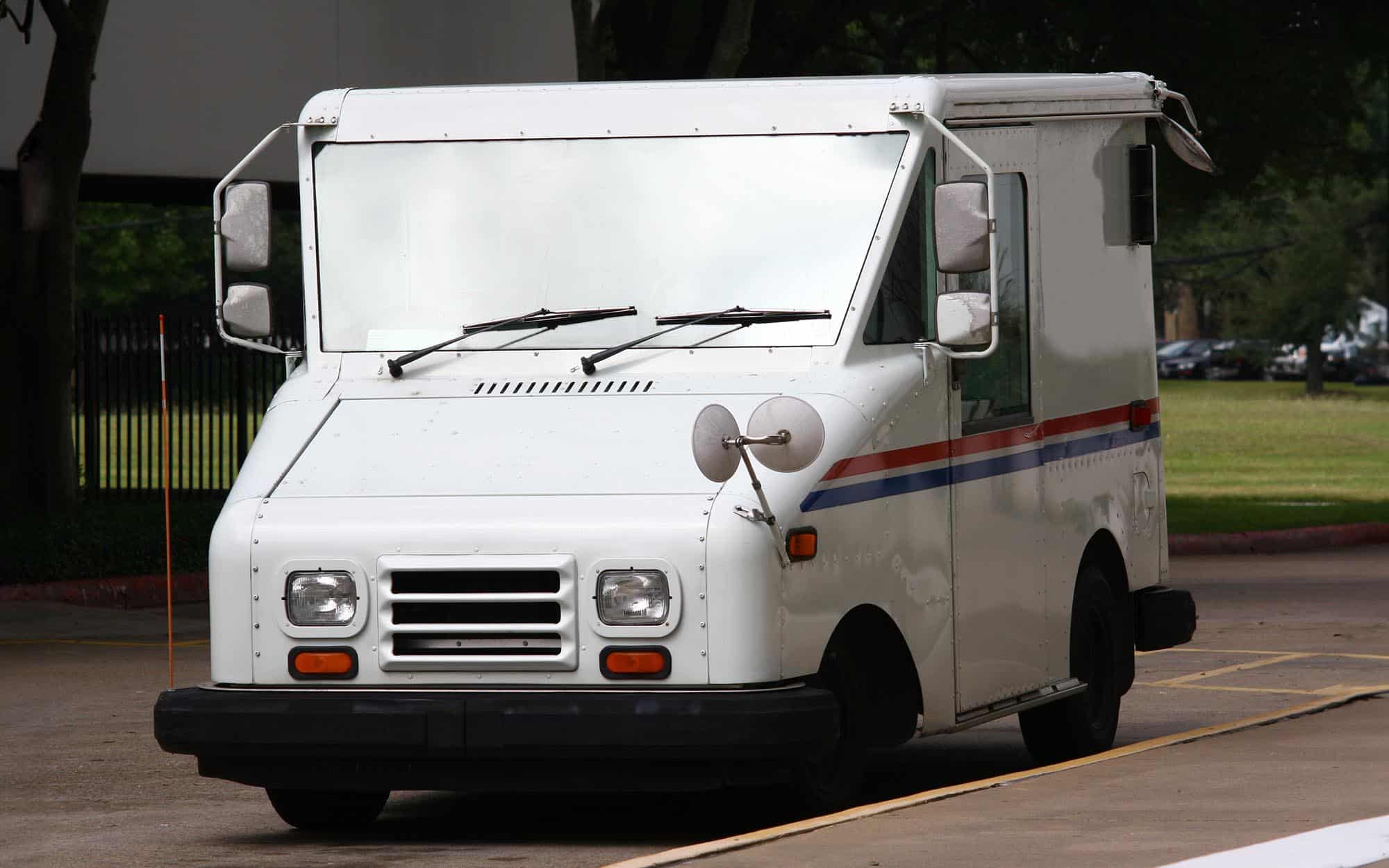 Side view of a mail truck driving down the road