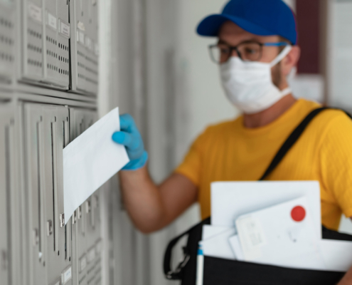 Mailman delivering mail with mail-bag and protective mask and gloves
