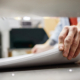 Close up of man putting stack of paper in printing machine at publishing shop, copy space