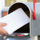Person putting mail in mailbox